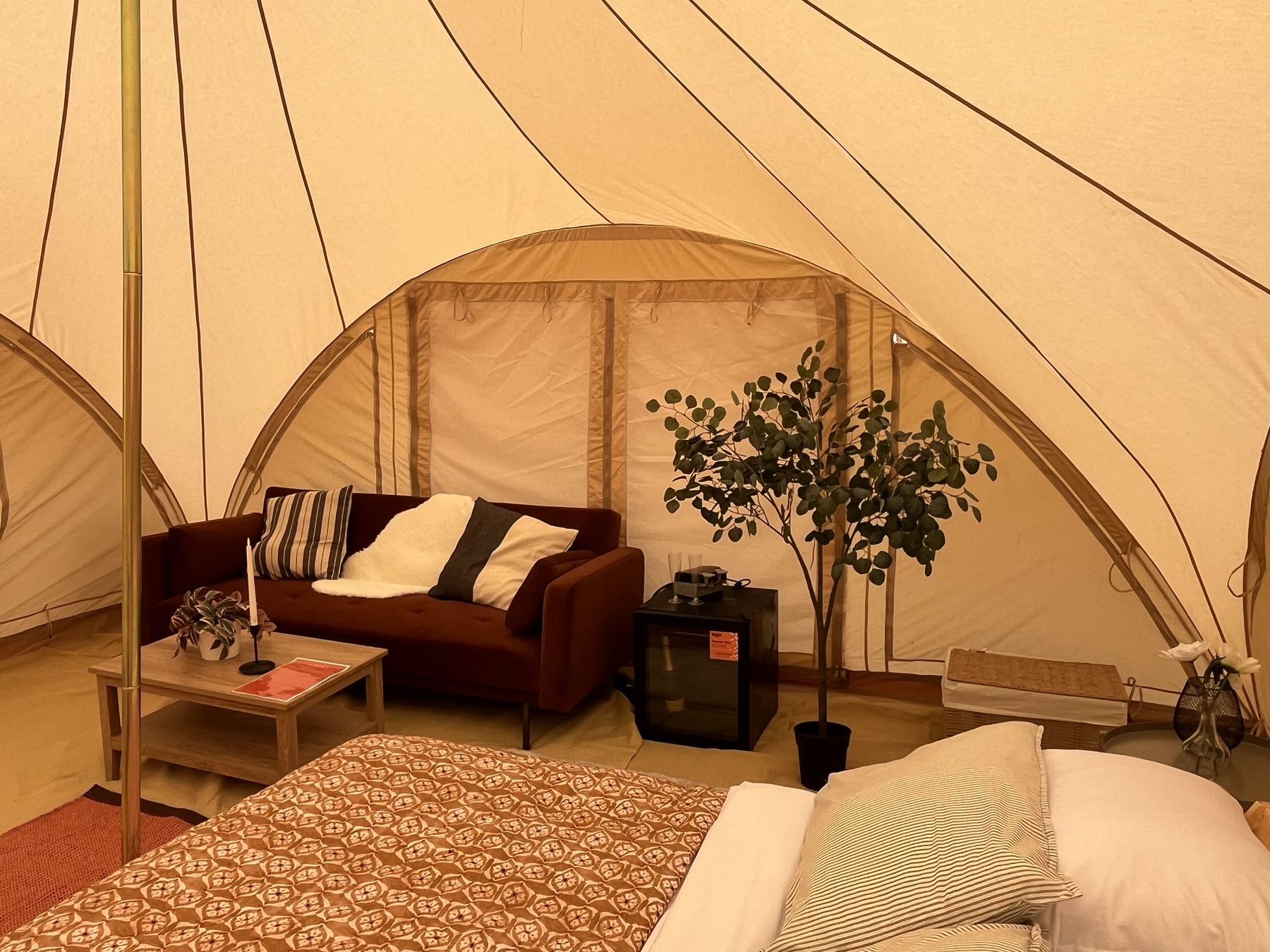 A wide view inside a tent, double bed made up with a console table
